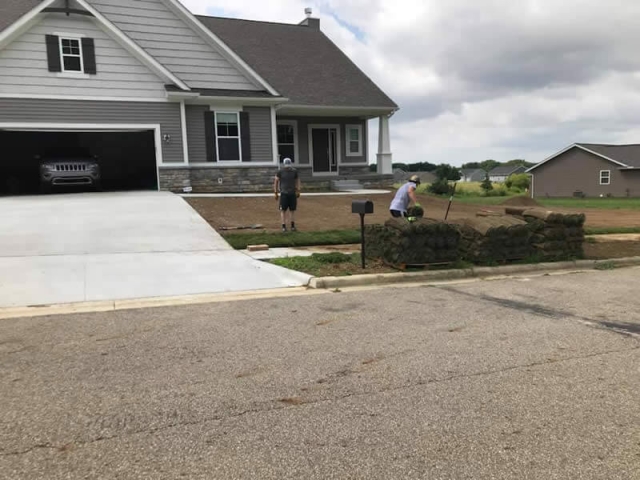 Natural Image Crew Installing Sod On Freshly Graded Front Lawn